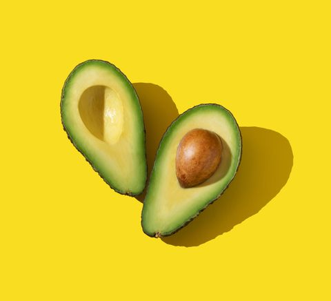 avocado halves with trendy lighting and hard shadow on yellow background