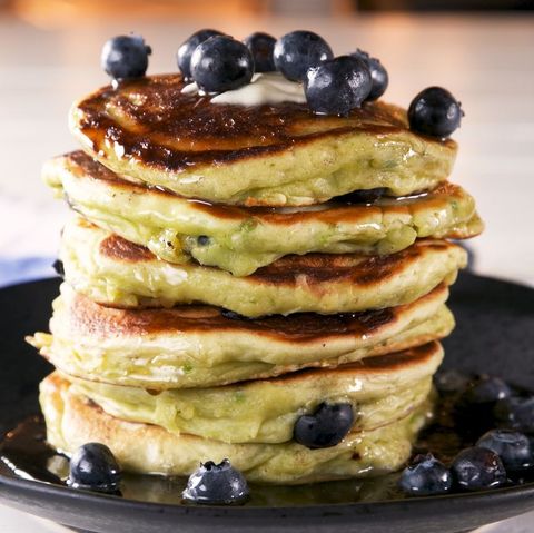 stack of avocado pancakes with blueberries on a black plate
