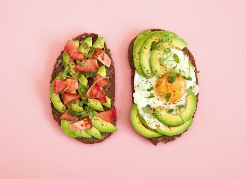two slices of avocado toast on pink background