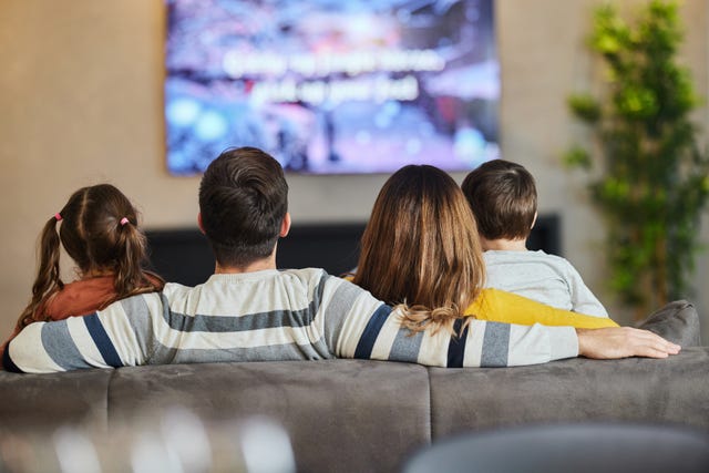 rear view of relaxed family watching tv on sofa in the living room