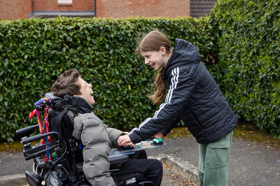 george in his wheelchair and friend freya looking at each other