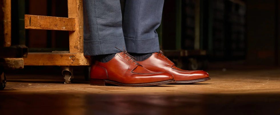 a pair of brown leather shoes worn with navy trousers