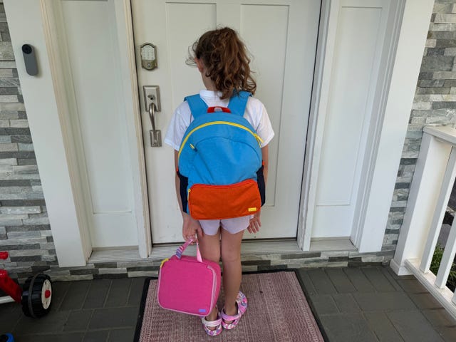 a girl wears the away blue backpack at her front door
