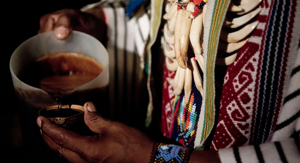 ﻿un chaman sirve un vaso de ayahuasca durante una ceremonia en colombia