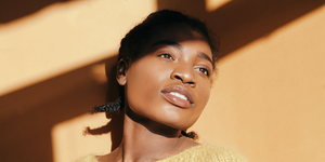 azelaic acid for skin   photo description a young black woman with smooth, bright skin standing in sunlight against a wall
