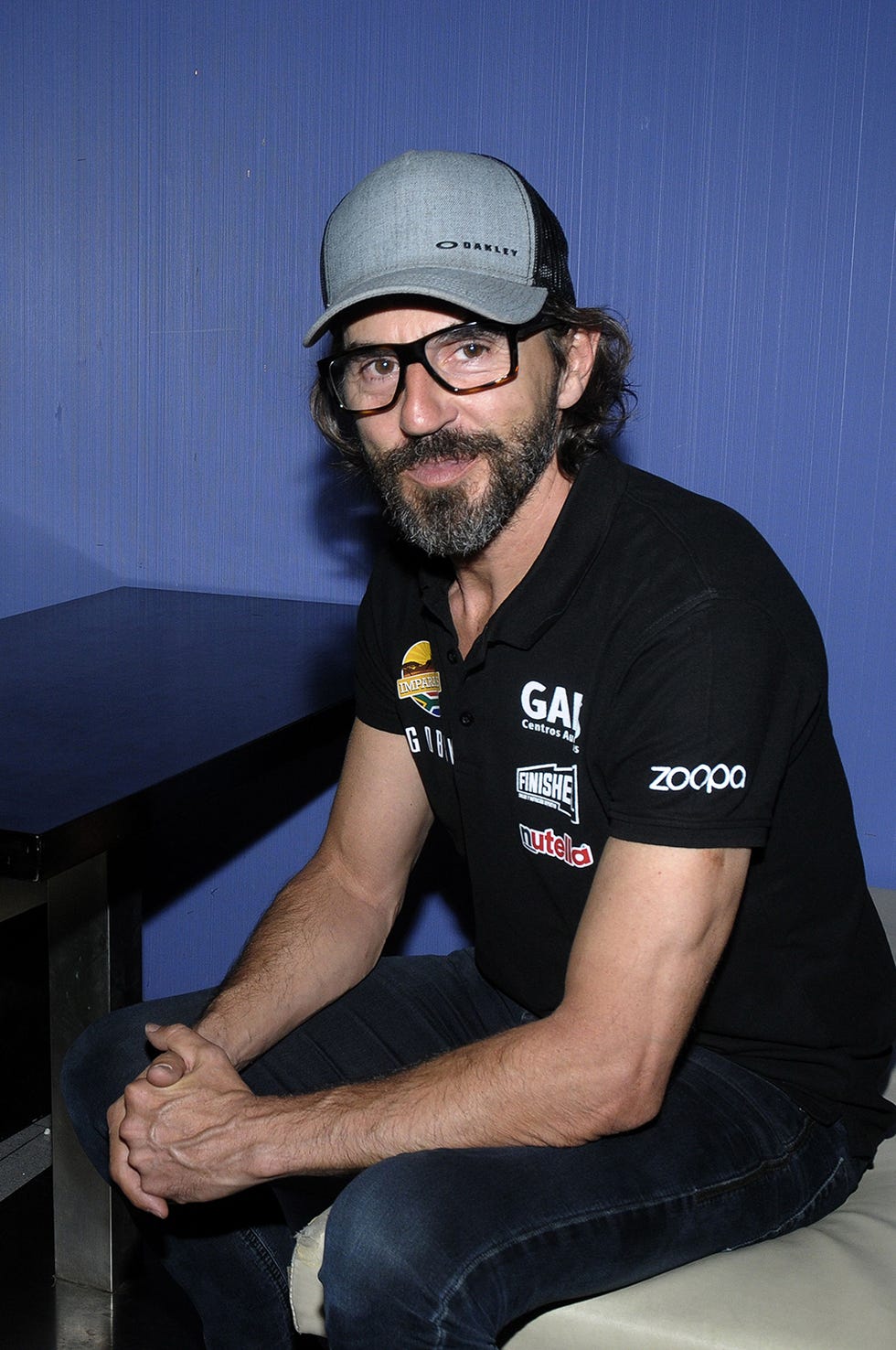 Facial hair, Arm, Beard, Headgear, Eyewear, Hat, Personal protective equipment, Sitting, Elbow, Glasses, 