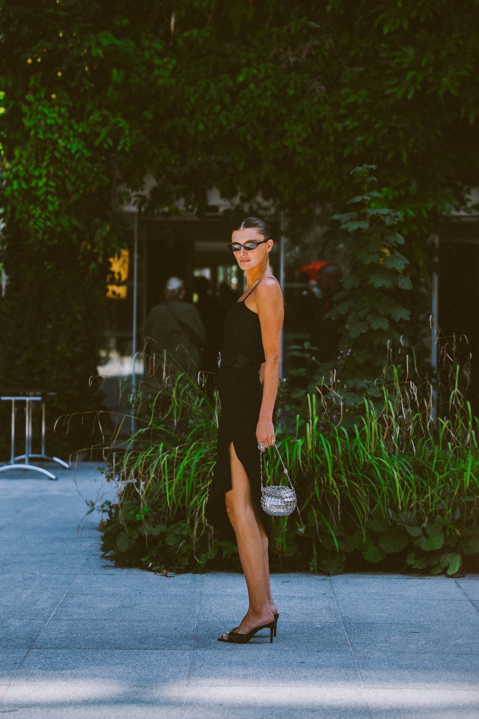person in a stylish black dress with a handbag in a vibrant outdoor setting
