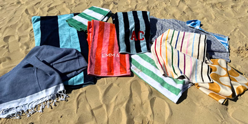 a variety of beach towels lying on sand