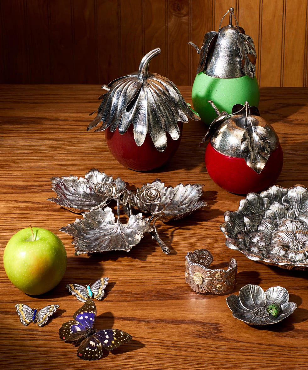 Decorative silver fruit and butterfly ornaments on a wooden table.
