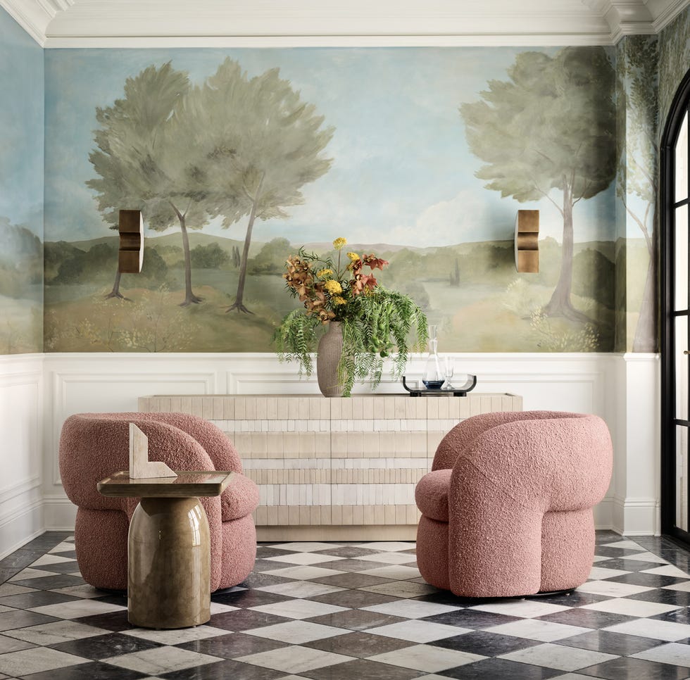 Living room interior featuring two plush chairs, a decorative vase, and a mural.