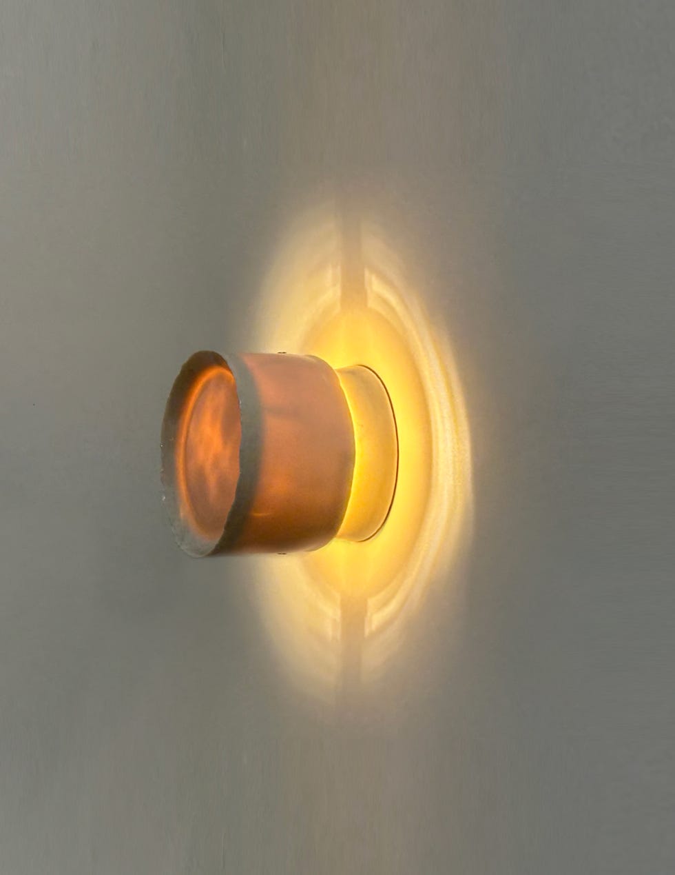 Cylindrical wall light illuminating its surroundings.