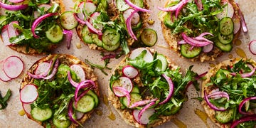bagel topped with baba ghanoush, sliced cucumber, arugula, and red onions