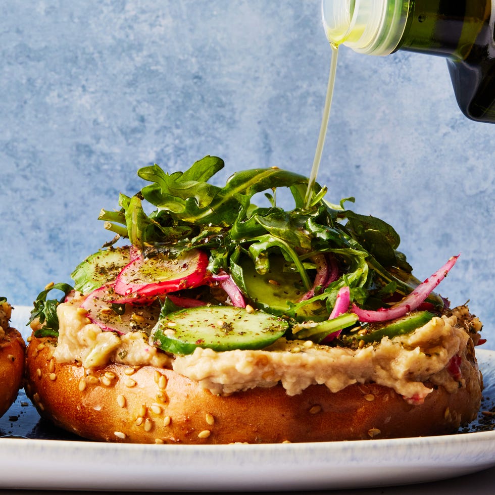 bagel topped with baba ghanoush, sliced cucumber, arugula, and red onions