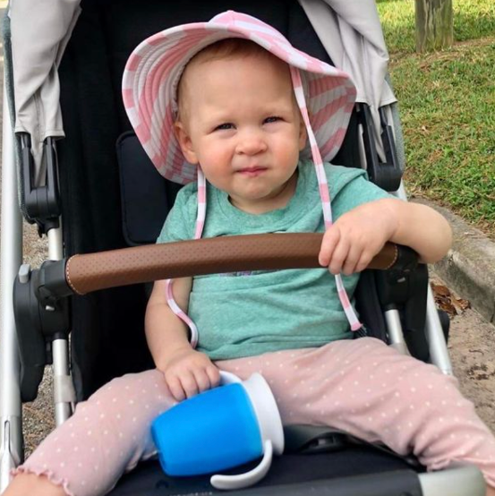 a toddler tests a sippy cup for good housekeeping a toddler sitting in a stroller tests a sippy cup for good housekeeping