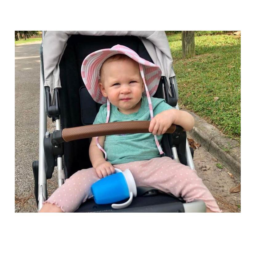 a toddler sitting in a stroller tests a sippy cup for good housekeeping