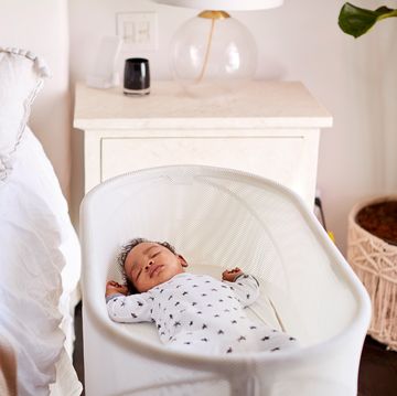 baby sleeping in bassinet next to bed