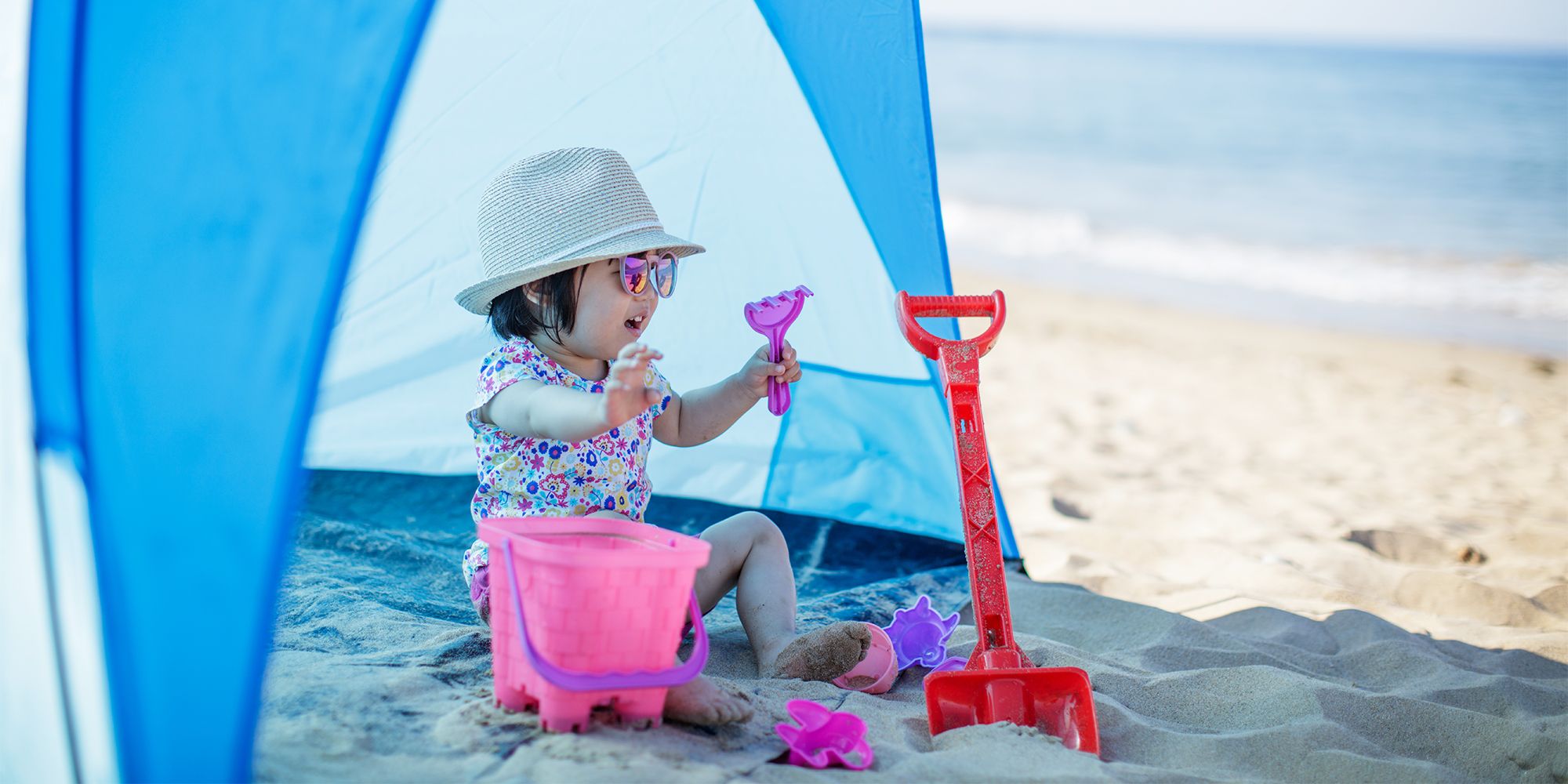 baby on beach sitting in front of a tent