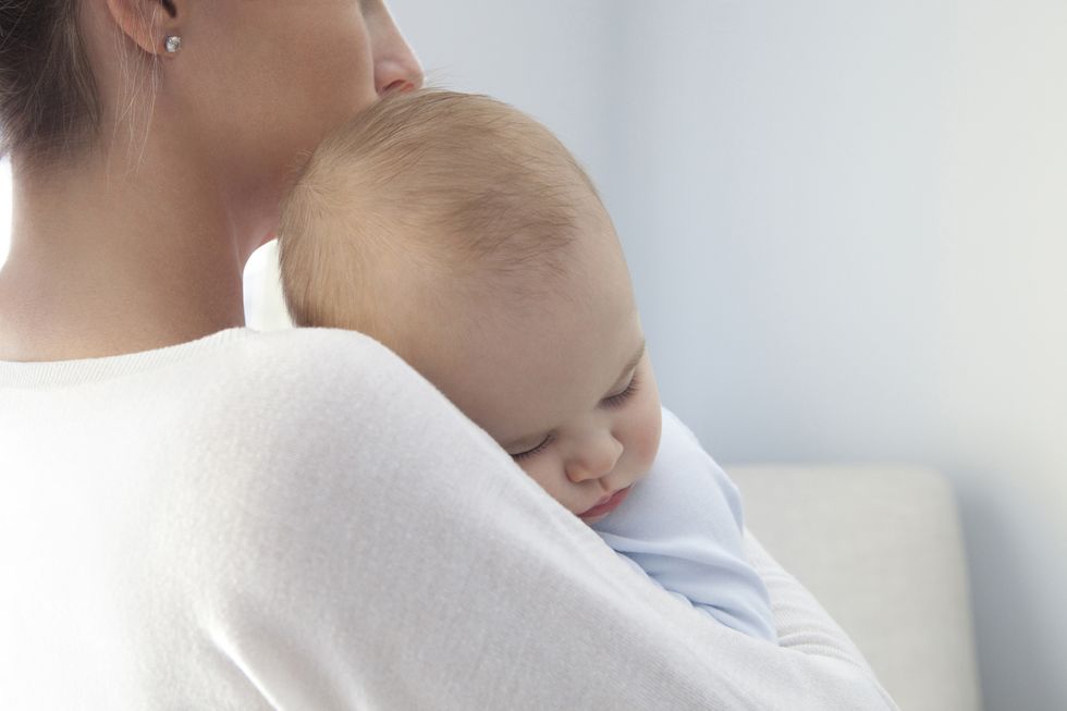 bebé enfermo durmiendo en los brazos de su madre