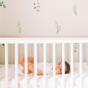 baby in white crib in boho nursery