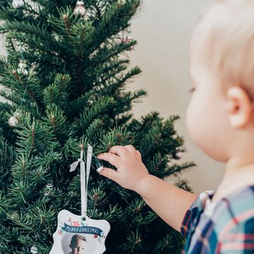 baby putting christmas ornament on tree