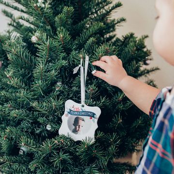 baby putting christmas ornament on tree