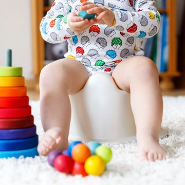 baby sitting in floor seat with wooden stacker toy and xylophone