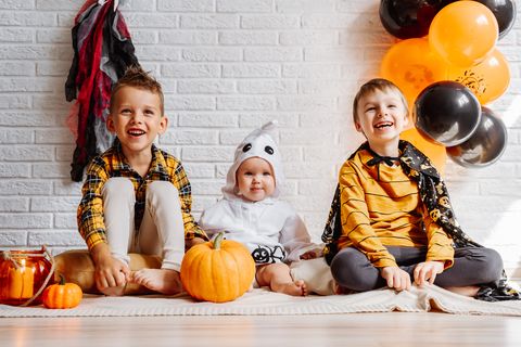children in costumes celebrate halloween white brick wall with decorations copy space