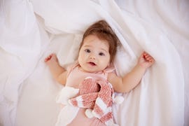 nina bebe tumbada con peluche