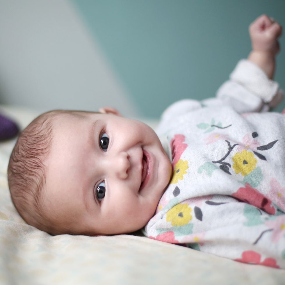 multicultural baby names, a baby girl smiling on a bed