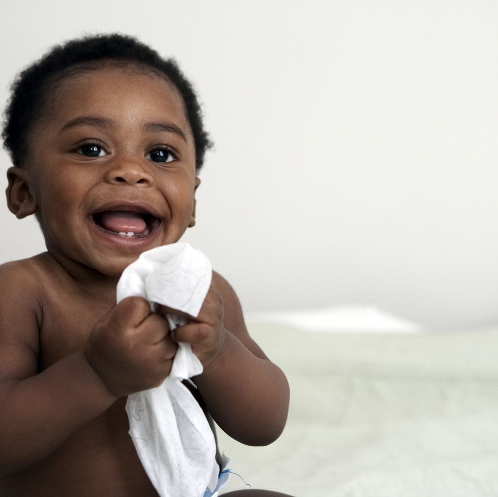 baby holding wipe smiling