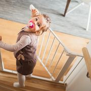 toddler looking up the stairs while opening baby gate