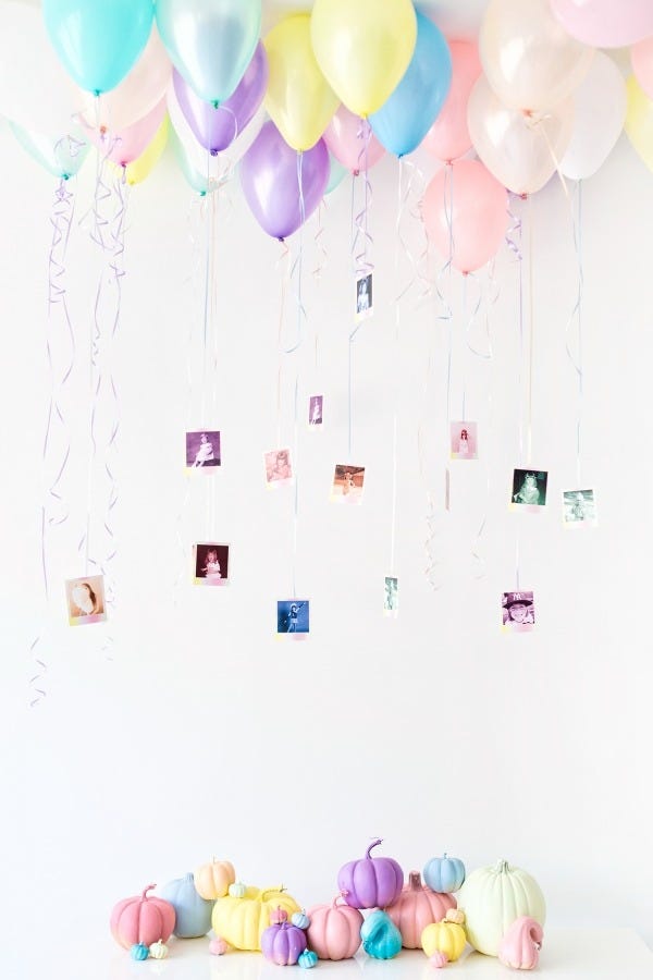 little photos hang from balloon strings over a collection of painted pastel pumpkins