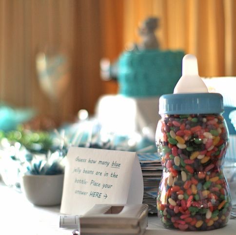 a baby boy shower game that has a baby bottle filled with jellybeans and a sign that says guess the number of blue jellybeans in the bottle