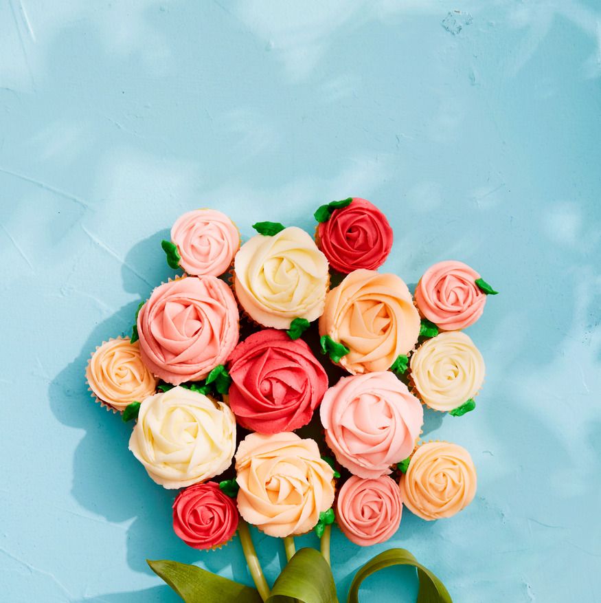 vanilla cupcakes with buttercream frosting in pinks and peaches that are arranged like a bouquet of roses
