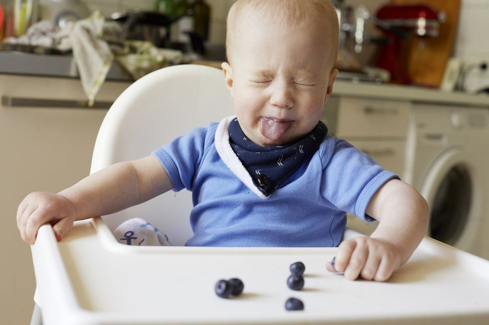 evita los alimentos duros y redondos como los arándanos, que el bebé de la foto no quiere comer, porque tiene riesgo de atrangantamiento