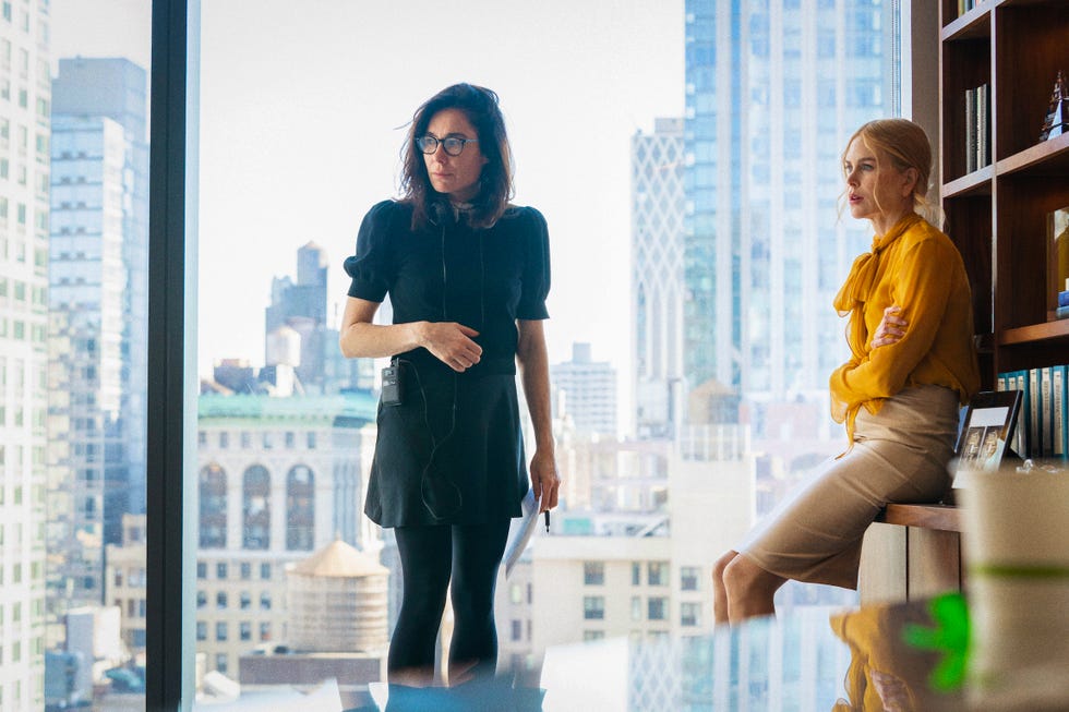 two women in a modern office setting with city view