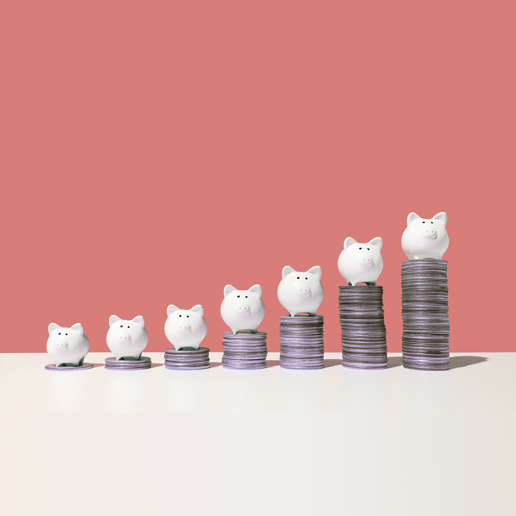 Little piggy banks on ascending stacks of coins
