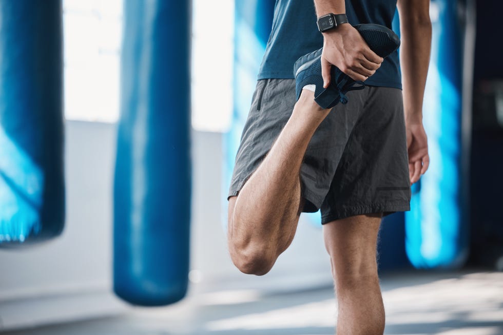 back, fitness and stretching with a sports man in the gym getting ready for a workout or training routine exercise, health and warm up with a male athlete in preparation of a workout for wellness