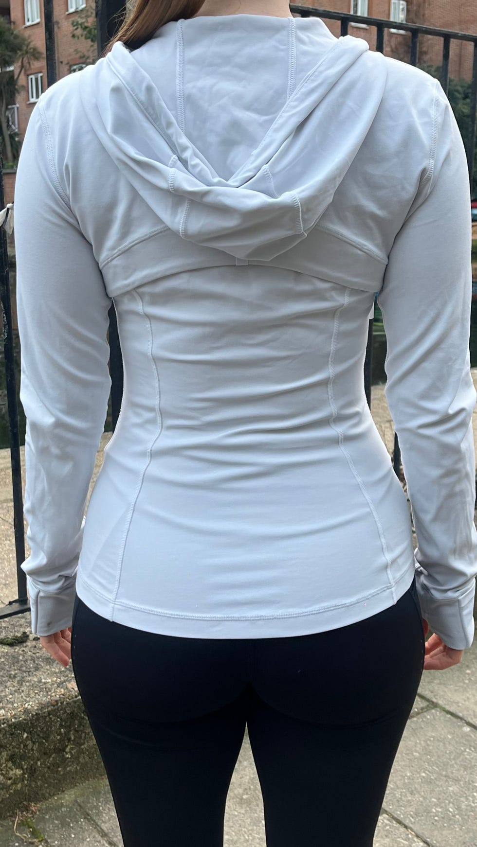 woman wearing a fitted white longsleeve top and black leggings viewed from behind