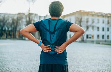 rug van persoon met sportkleding, handen op zijn onderrug