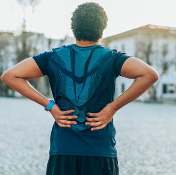 oefeningen onderrug rug van persoon met sportkleding, handen op zijn onderrug