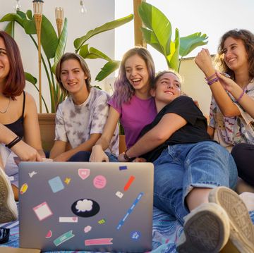 group of teens sitting on a blanket with a laptop