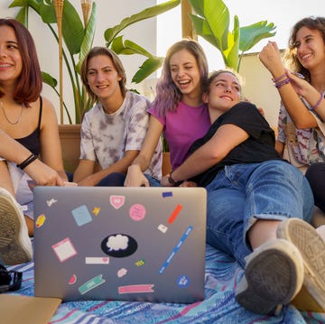 group of teens sitting on a blanket with a laptop