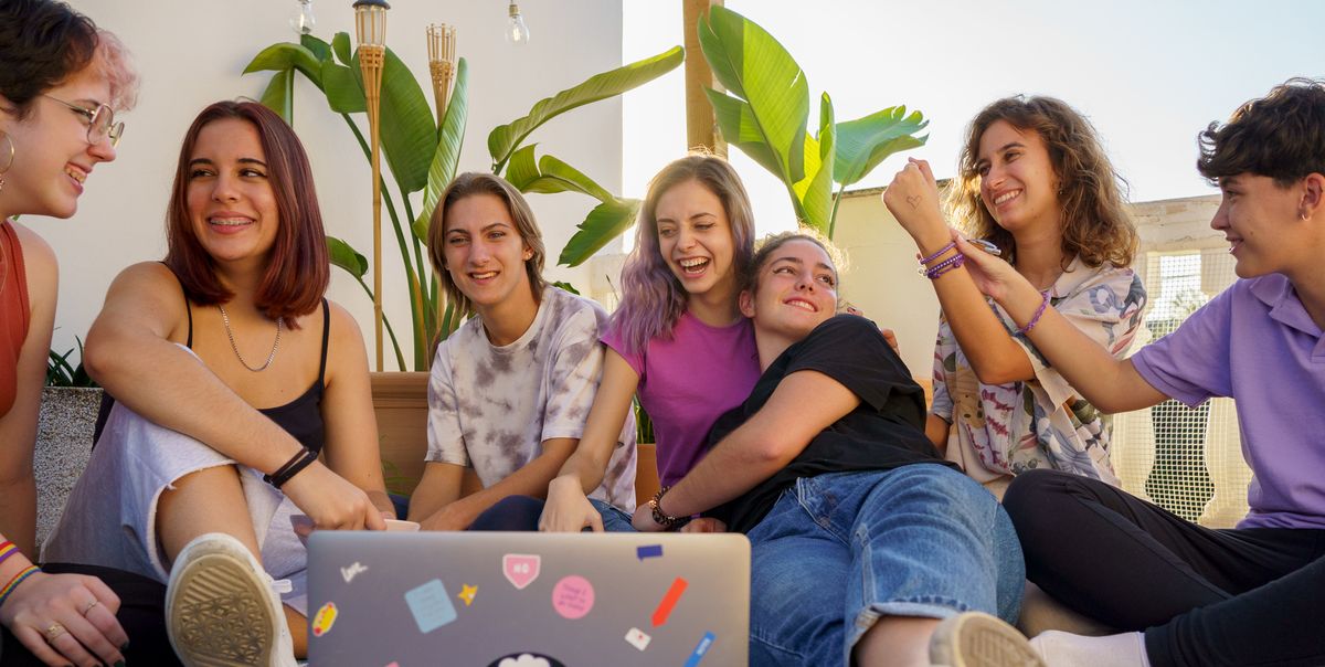 group of teens sitting on a blanket with a laptop