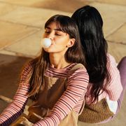 teen girl blowing bubble with gum in striped shirt and overalls