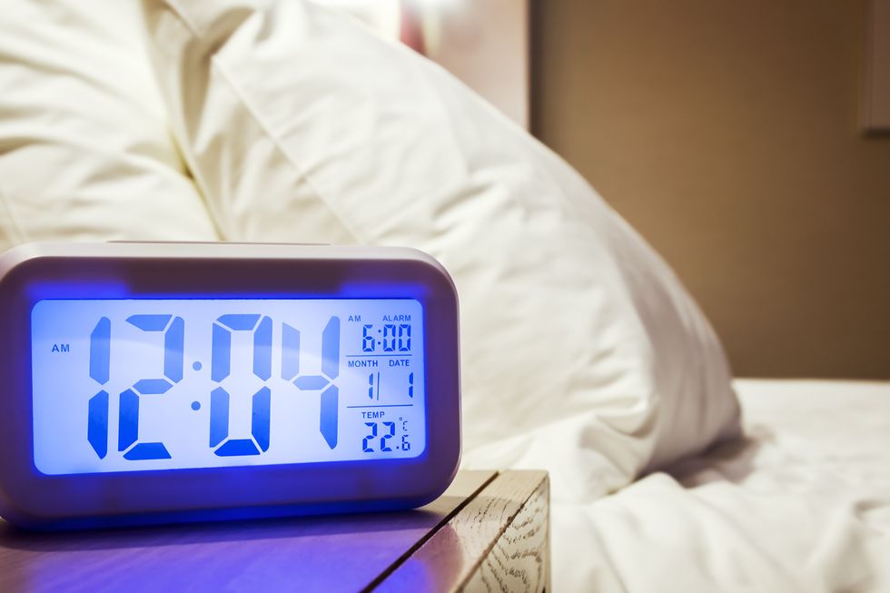 electronic alarm clock stands on a bedside table in the room