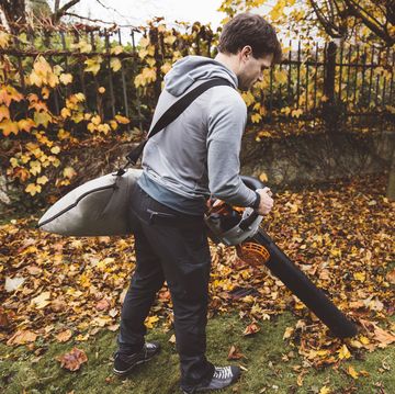 back view of a man vacuuming crispy leaves with leaf vacuum