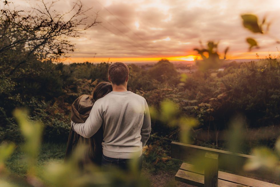 Back view of couple in love in autumnal nature watching sunset