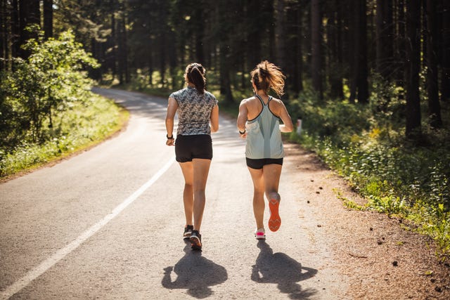 what causes a side stitch while running back view of female athletes running on road in forest