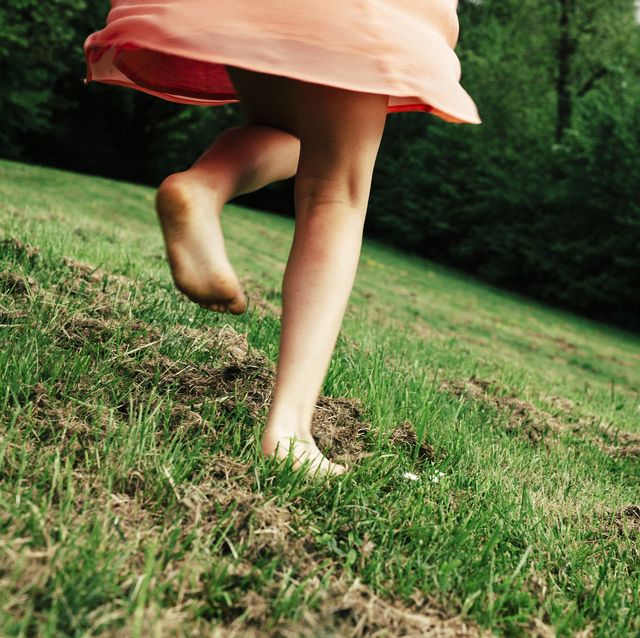 back view of girl running barefoot on a meadow, partial view